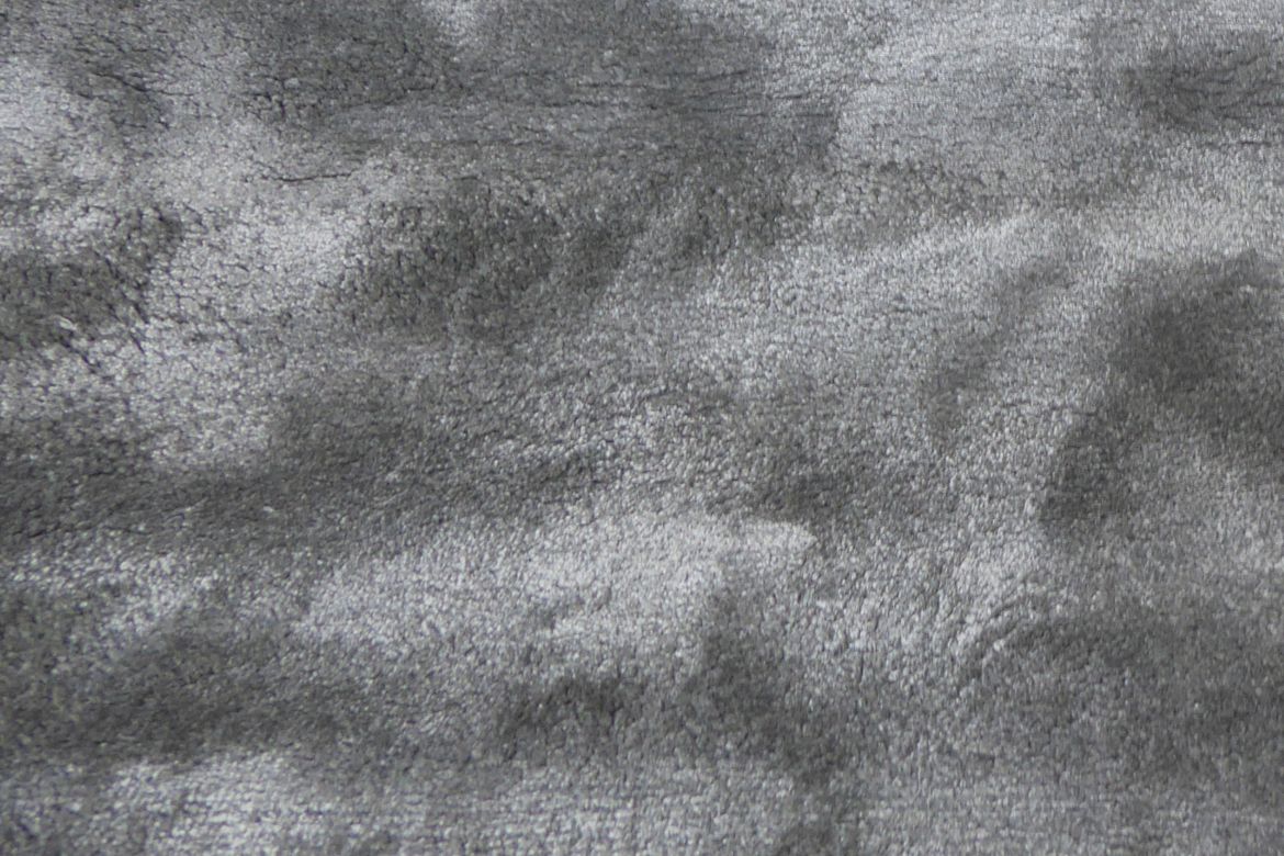 Gros plan sur la texture brillante du tapis gris en viscose, fibres fines et soyeuses
