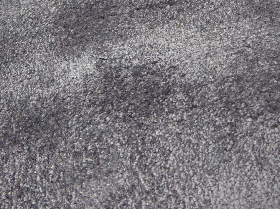 Gros plan sur la surface brillante et douce du tapis en viscose gris, soulignant ses nuances de couleur