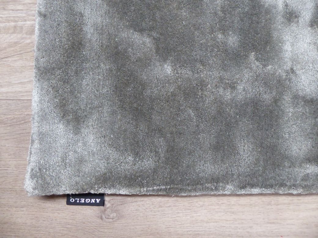 Tapis en viscose gris photographié sous un angle de coin, mettant en avant sa brillance et ses proportions