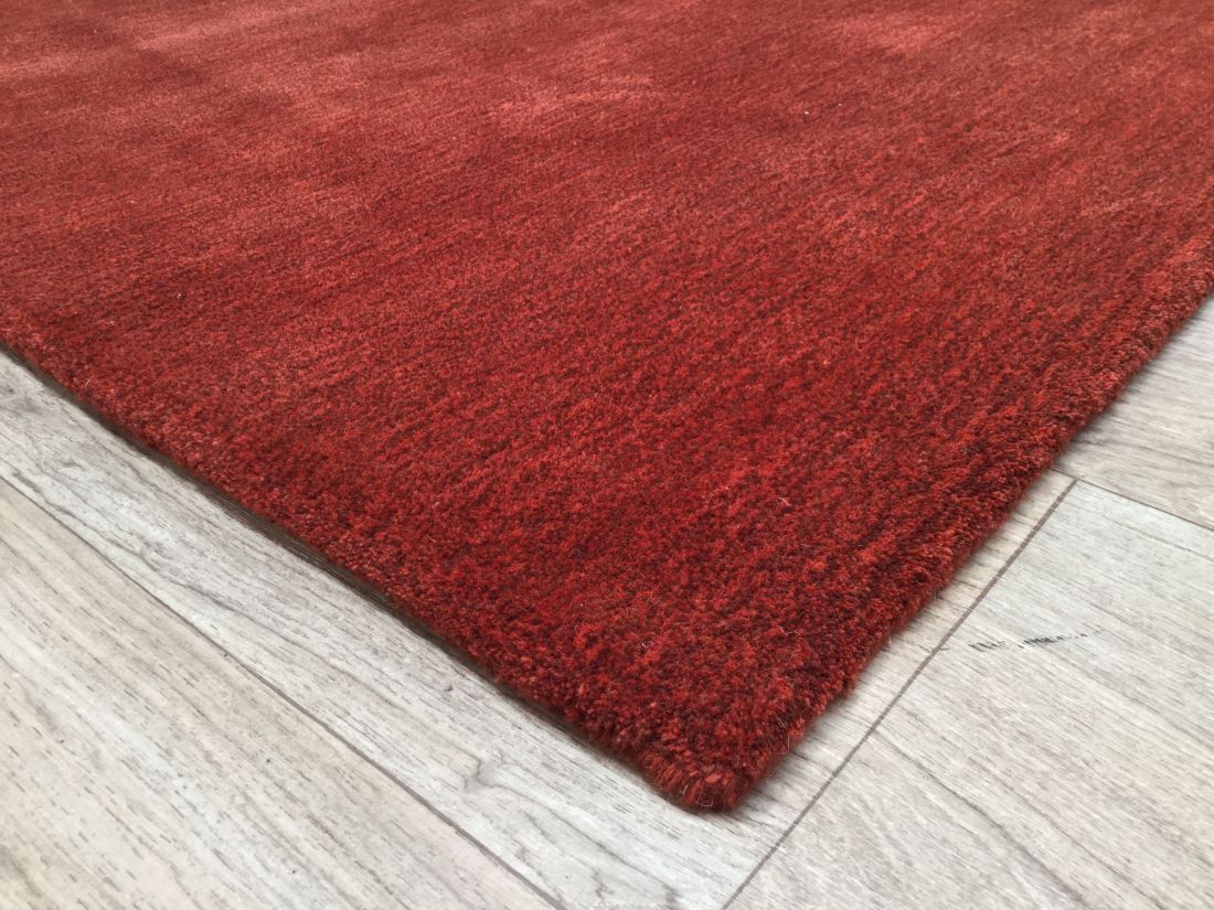 Vue d’angle du tapis rouge en laine et viscose, montrant la bordure et la profondeur de la matière