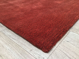 Vue d’angle du tapis rouge en laine et viscose, montrant la bordure et la profondeur de la matière