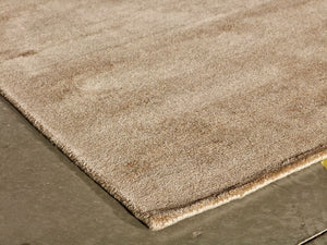 Détail du tapis sable en viscose vu de coin, texture lumineuse et finitions haut de gamme