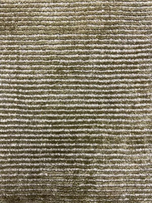 Gros plan sur la texture du tapis argent vert, mélange de laine et de polyamide, révélant son éclat et sa douceur