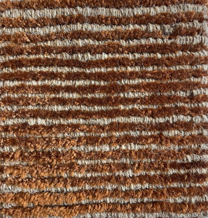 Détail du tapis terracotta beige – gros plan sur la texture brillante en laine et polyamide, effet doux et lumineux