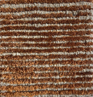 Détail du tapis terracotta beige – gros plan sur la texture brillante en laine et polyamide, effet doux et lumineux