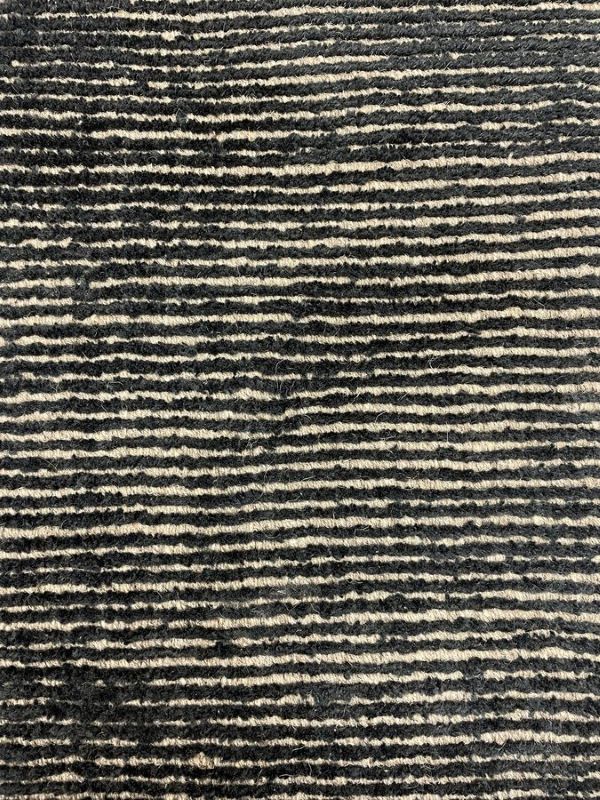 Gros plan sur la texture du tapis or noir – détails du tissage mêlant laine et polyamide, effet brillant et sophistiqué