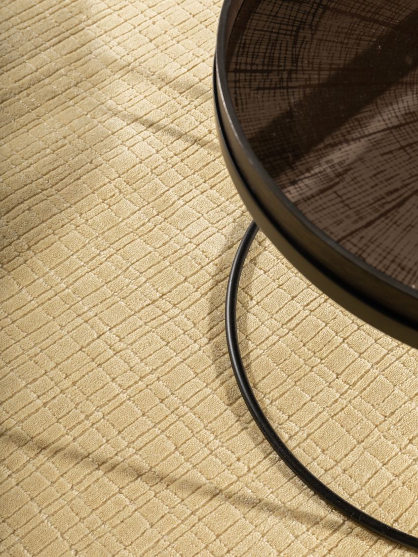 Tapis beige jaune pâle avec table basse, soulignant son style élégant et sa durabilité en PET recyclé