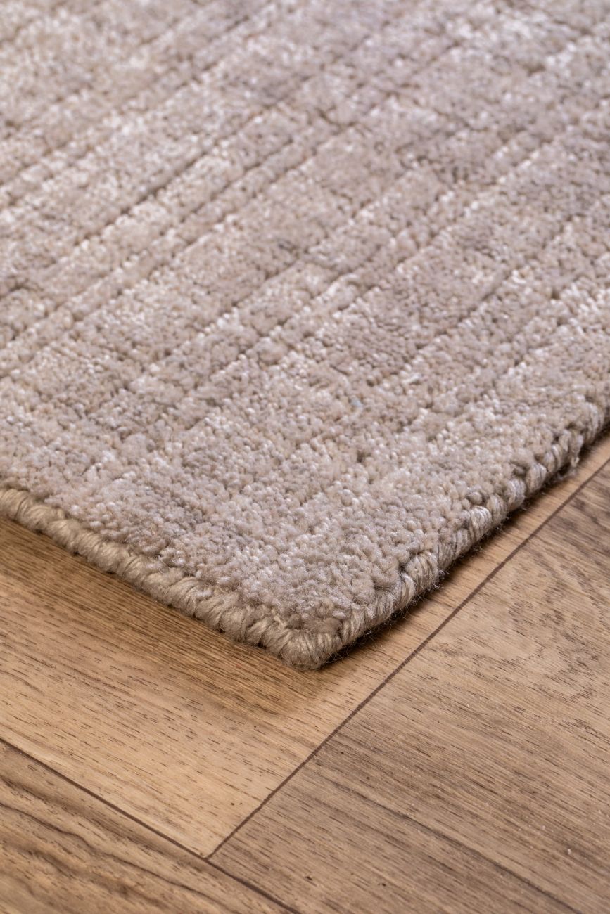 Tapis rose pâle en PET recyclé vu en angle, montrant texture tissée, finitions raffinées et motif subtil