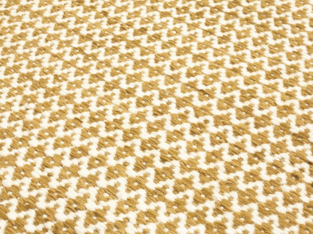 Gros plan sur tapis tissé plat en laine, texture naturelle, motif losange géométrique jaune et blanc