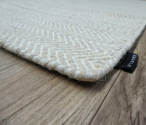Tapis plat en laine de Nouvelle-Zélande, tissage artisanal, design géométrique beige et blanc, présenté en angle