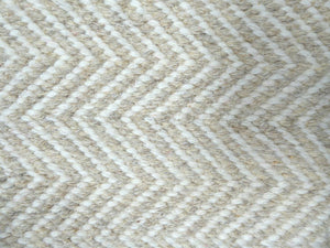 Détail du tissage artisanal du tapis en laine de Nouvelle-Zélande, motif zigzag géométrique subtil beige clair et blanc