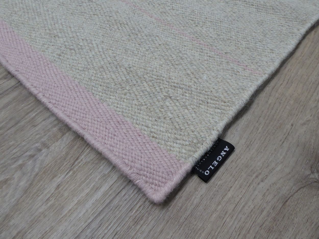 Coin du tapis tissé main gris rose – détail de la finition et des rayures délicates en perspective