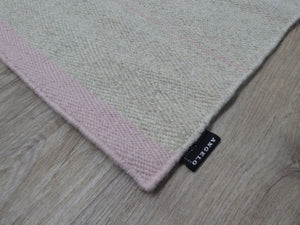 Coin du tapis tissé main gris rose – détail de la finition et des rayures délicates en perspective