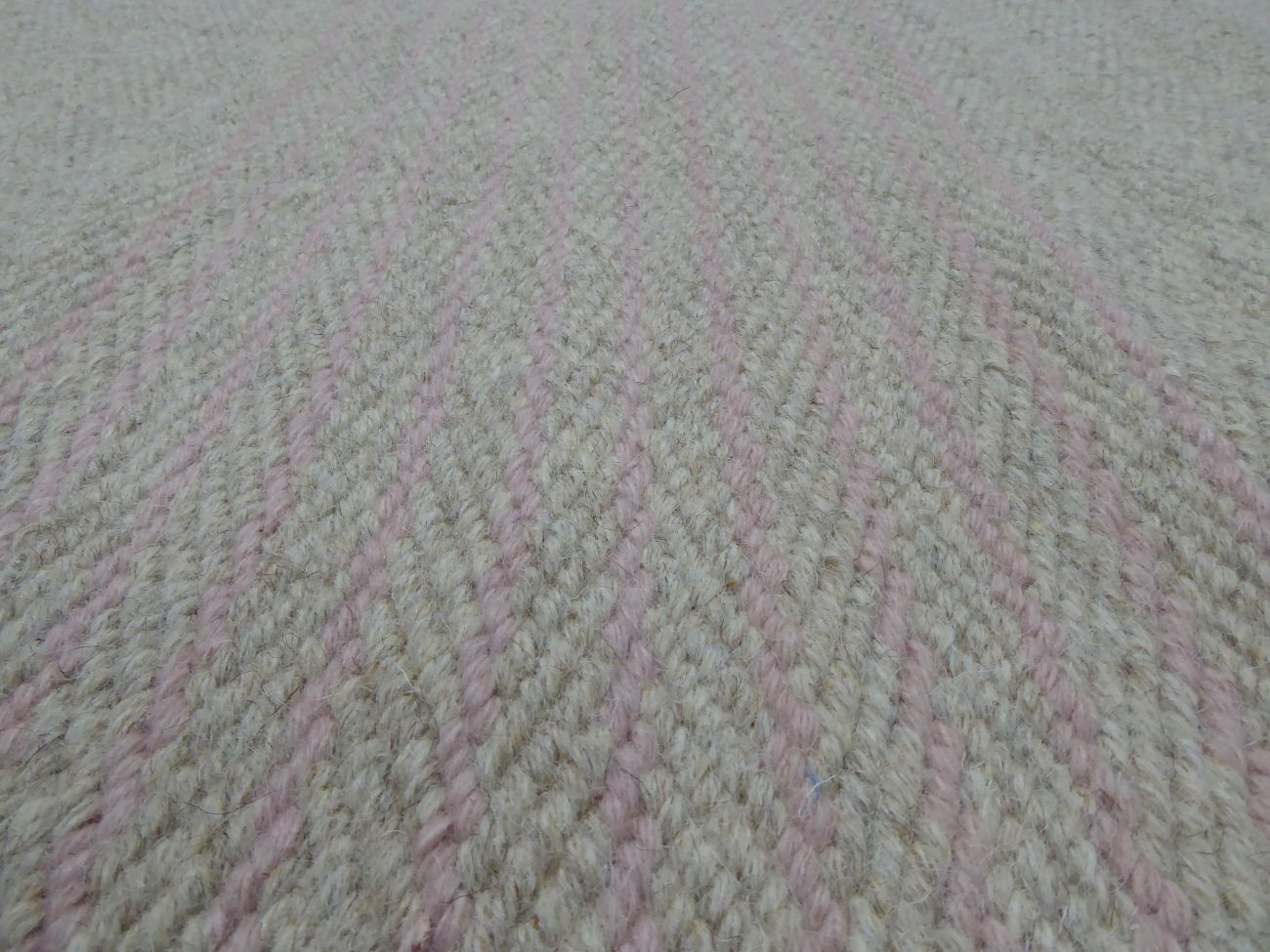 Gros plan sur la texture du tapis tissé main – fibres artisanales et rayures raffinées gris rose