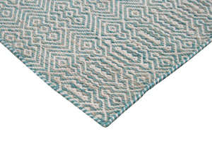 Tapis blanc et turquoise en PET recyclé vu de coin, motifs géométriques et texture résistante, adapté intérieur et extérieur