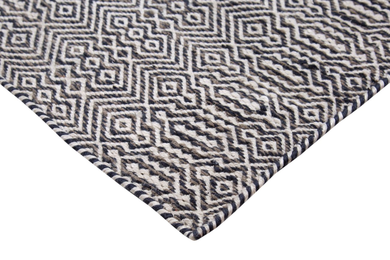 Tapis géométrique en PET recyclé blanc, gris et marine, vue en angle, texture adaptée au salon, terrasse ou balcon