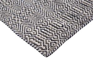 Tapis géométrique en PET recyclé blanc, gris et marine, vue en angle, texture adaptée au salon, terrasse ou balcon