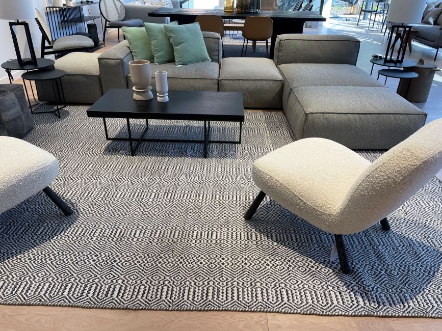 Tapis ethnique en PET recyclé blanc, gris et marine installé dans un salon moderne, ambiance conviviale, matière durable