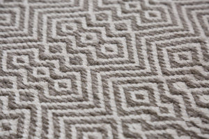 Gros plan sur tapis en PET recyclé blanc et gris, détails des motifs géométriques et texture résistante