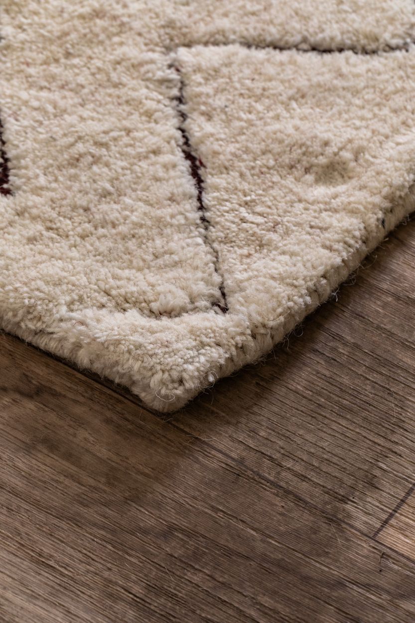 Tapis en laine ivoire à formes géométriques, aperçu en coin mettant en valeur l’épaisseur et les finitions artisanales