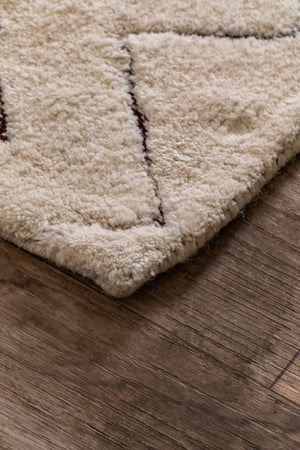 Tapis en laine ivoire à formes géométriques, aperçu en coin mettant en valeur l’épaisseur et les finitions artisanales