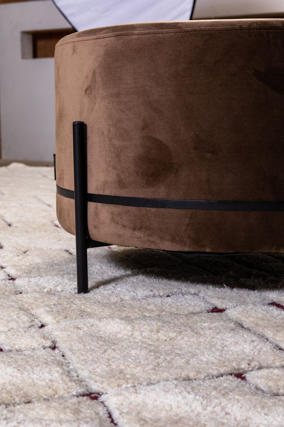 Tapis ivoire à motifs géométriques en laine, présenté dans un intérieur avec un siège pour suggérer l’ambiance cosy et élégante