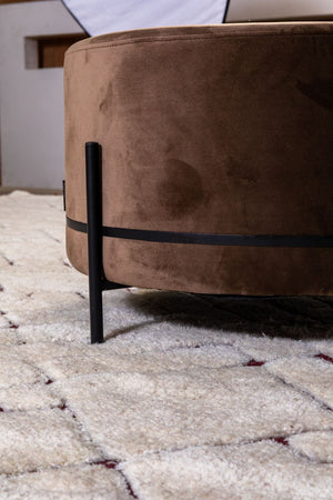 Tapis ivoire à motifs géométriques en laine, présenté dans un intérieur avec un siège pour suggérer l’ambiance cosy et élégante