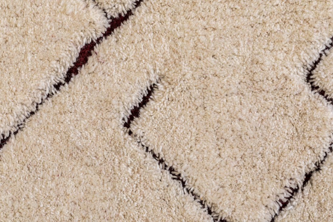 Gros plan sur la texture du tapis ivoire en laine, détails des motifs géométriques et du tissage doux et dense