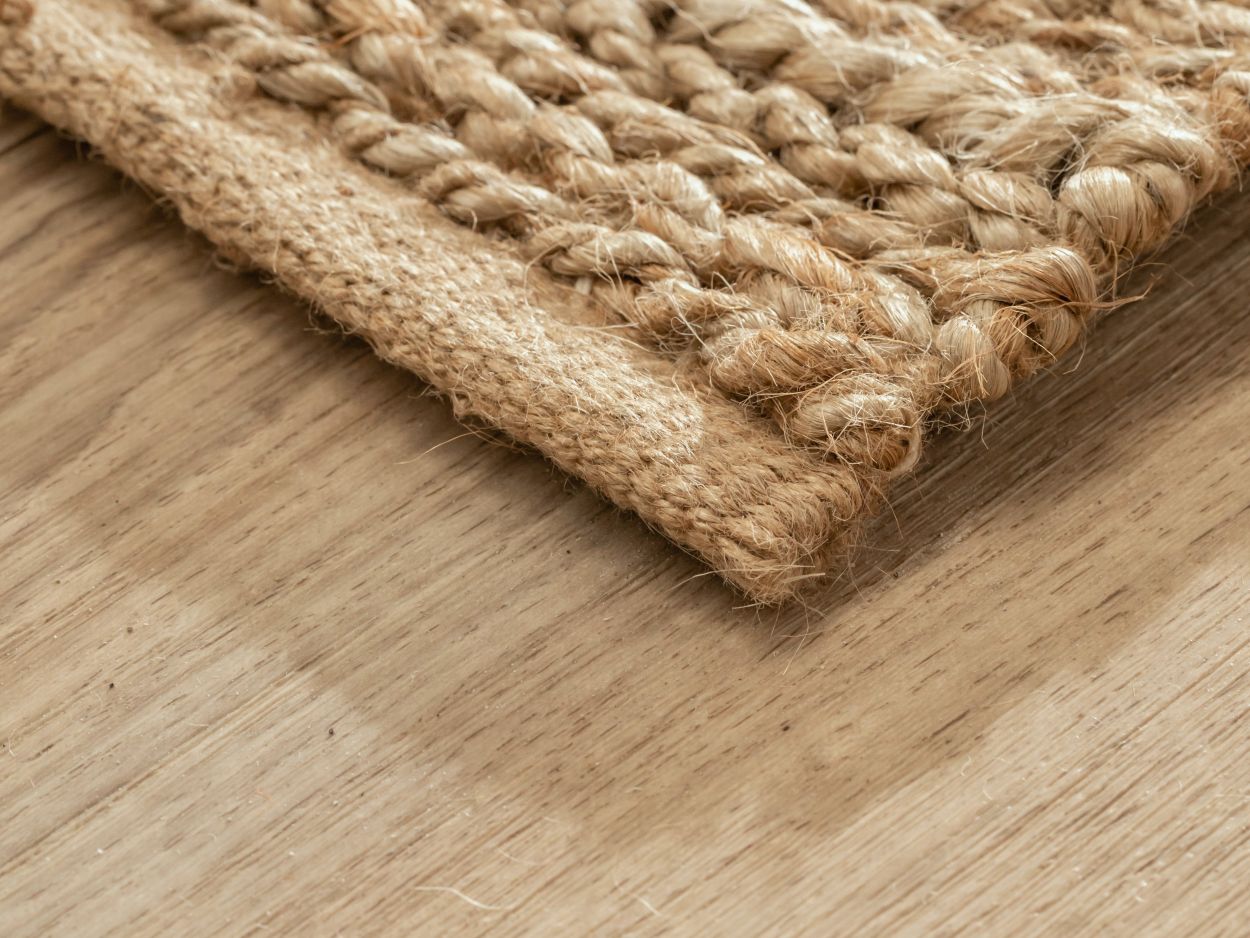 Gros plan sur le coin du tapis d’été beige en jute, montrant la finition soignée et les fibres naturelles