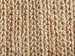 Détail de la texture du tapis en jute beige, fibres tressées et nuances naturelles du matériau