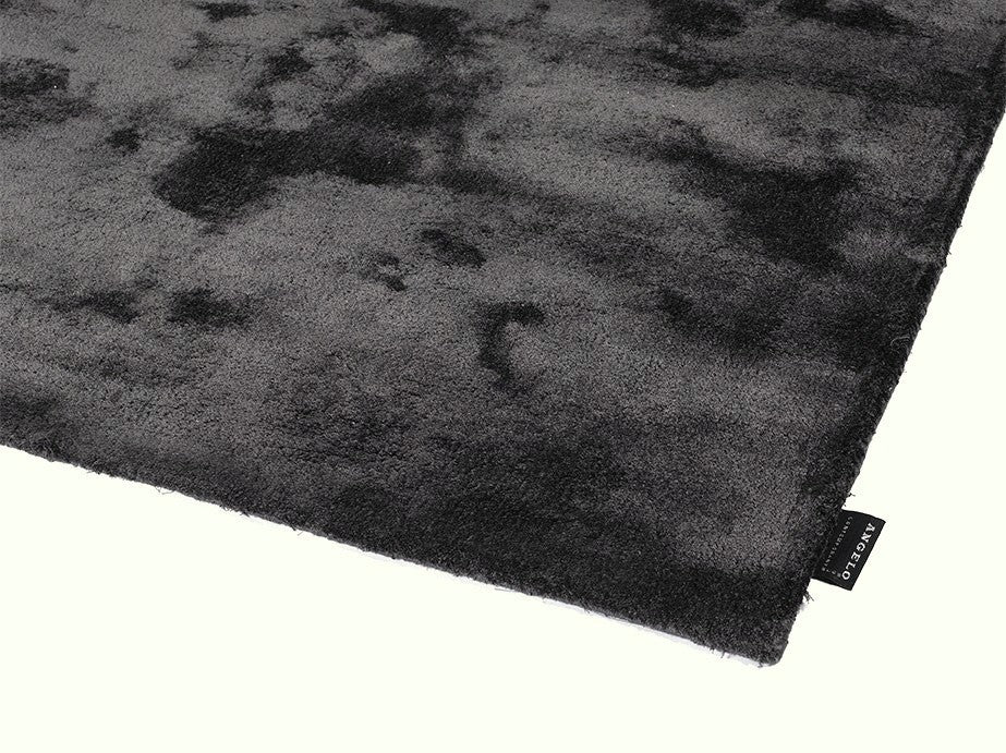 Vue en coin d’un tapis gris foncé en bambou tissé à la main, aux reflets brillants et finitions soignées