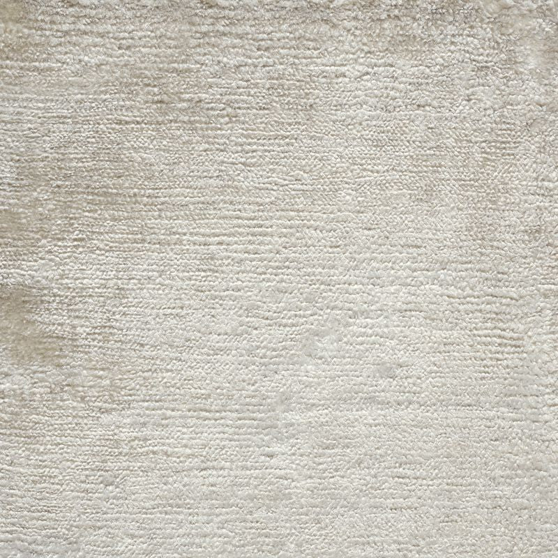 Gros plan sur la texture soyeuse du tapis en soie de bambou ivoire, révélant la finesse du tissage et la douceur