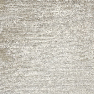 Gros plan sur la texture soyeuse du tapis en soie de bambou ivoire, révélant la finesse du tissage et la douceur