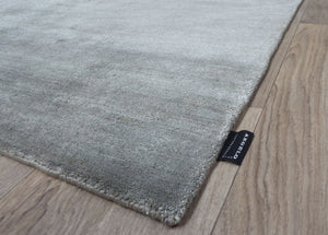 Tapis en soie de bambou gris argenté vu de coin, mettant en valeur la profondeur et la brillance du textile