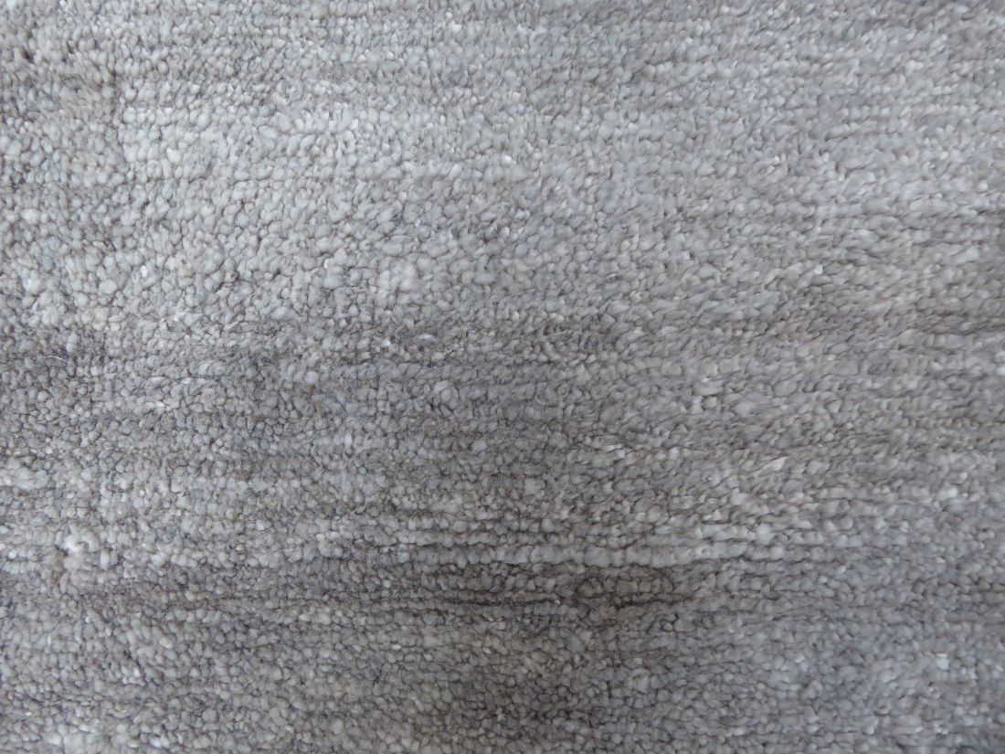Gros plan sur la texture soyeuse et raffinée du tapis en soie de bambou gris argenté