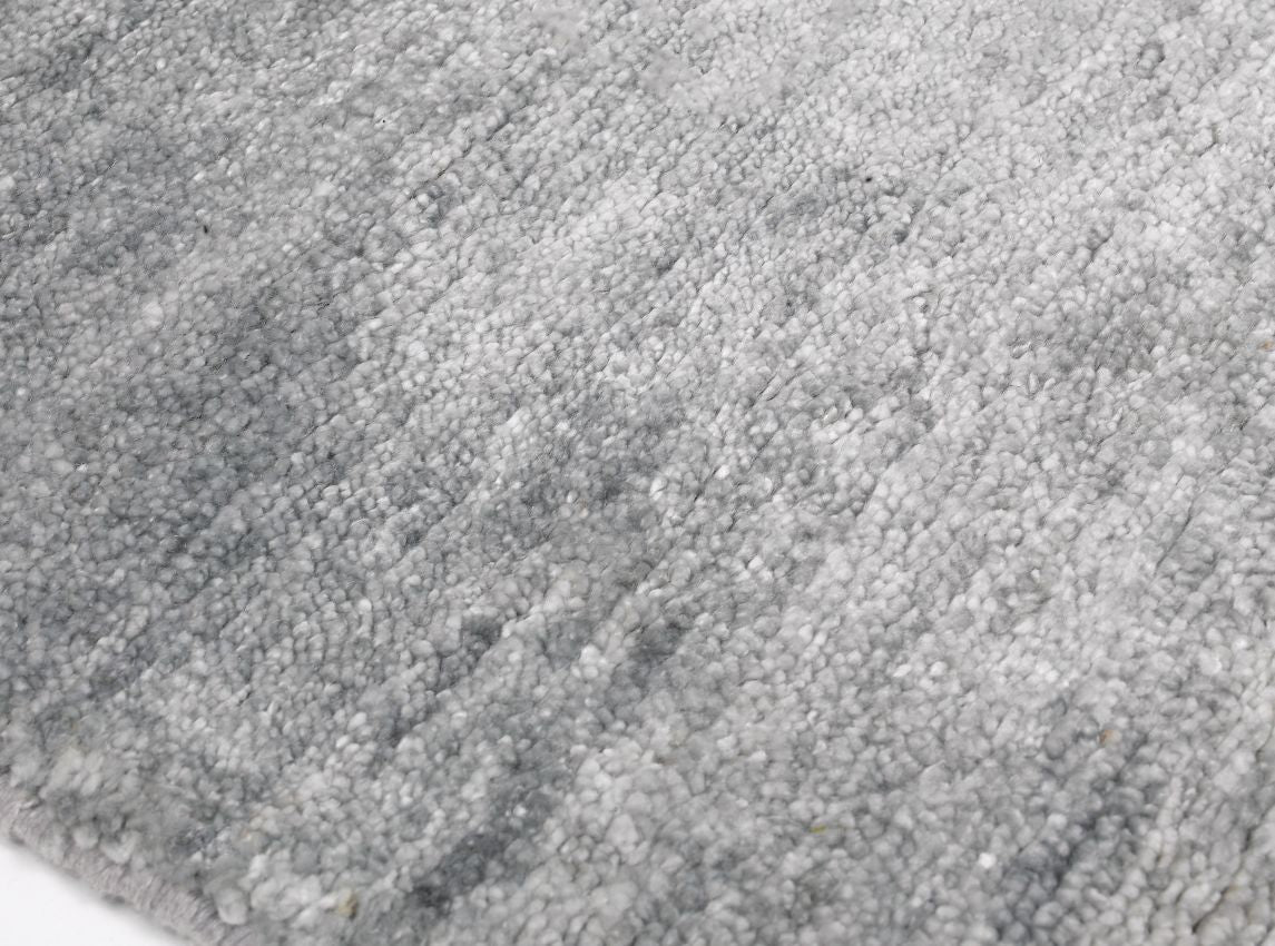 Tapis de luxe en soie de bambou gris raffiné, vue de bord révélant ses finitions et son épaisseur