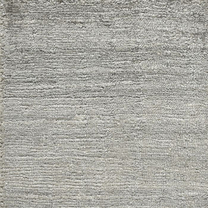 Gros plan sur la texture soyeuse d’un tapis en soie de bambou gris, mettant en valeur sa brillance et son tissage fin