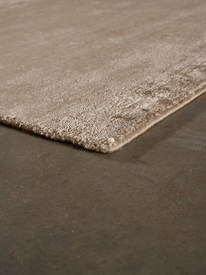 Tapis en soie de bambou marron clair, en vue d’angle, reflétant sa brillance délicate et ses finitions haut de gamme