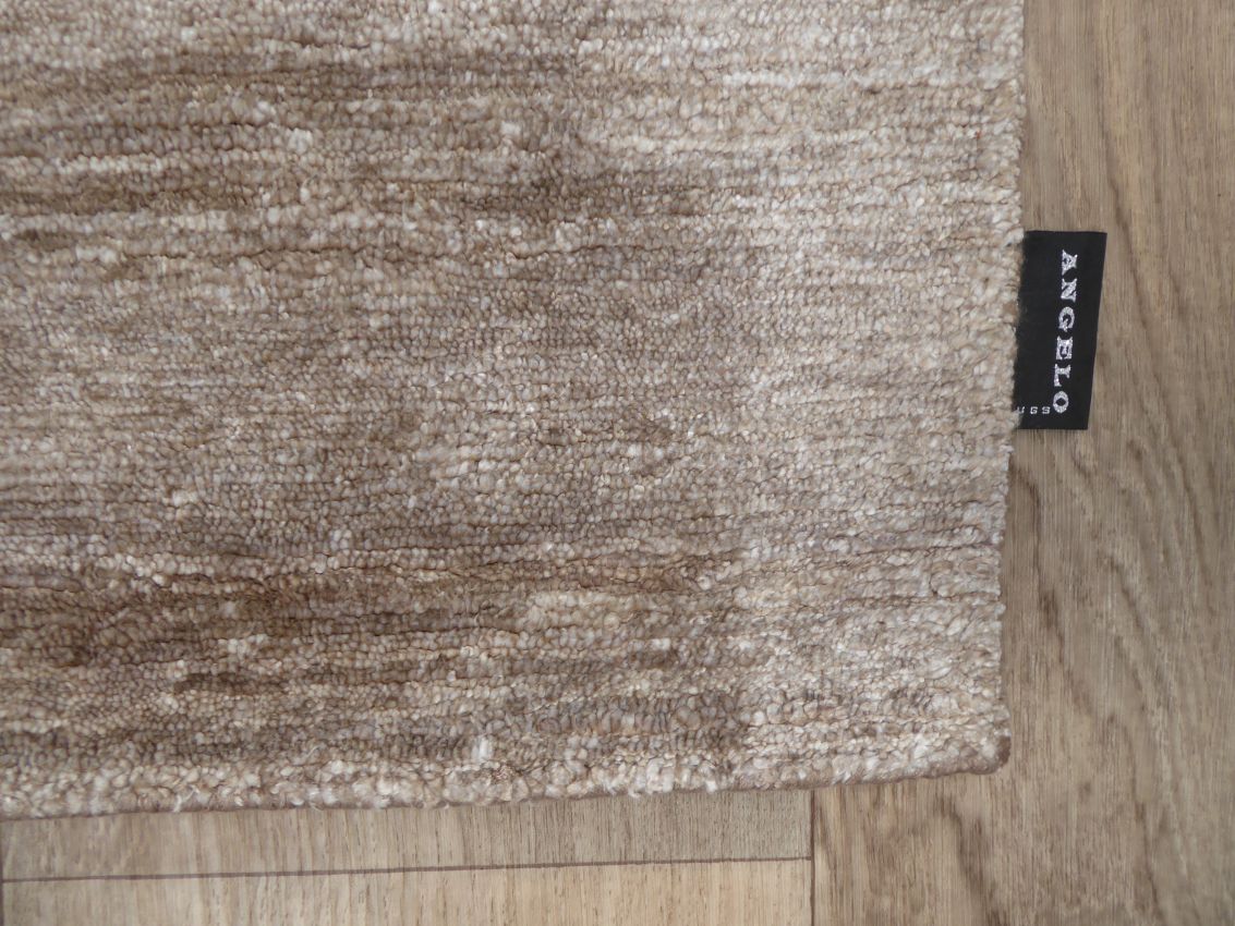 Gros plan sur la texture soyeuse du tapis en soie de bambou marron clair, révélant les fibres fines et la finition luxueuse