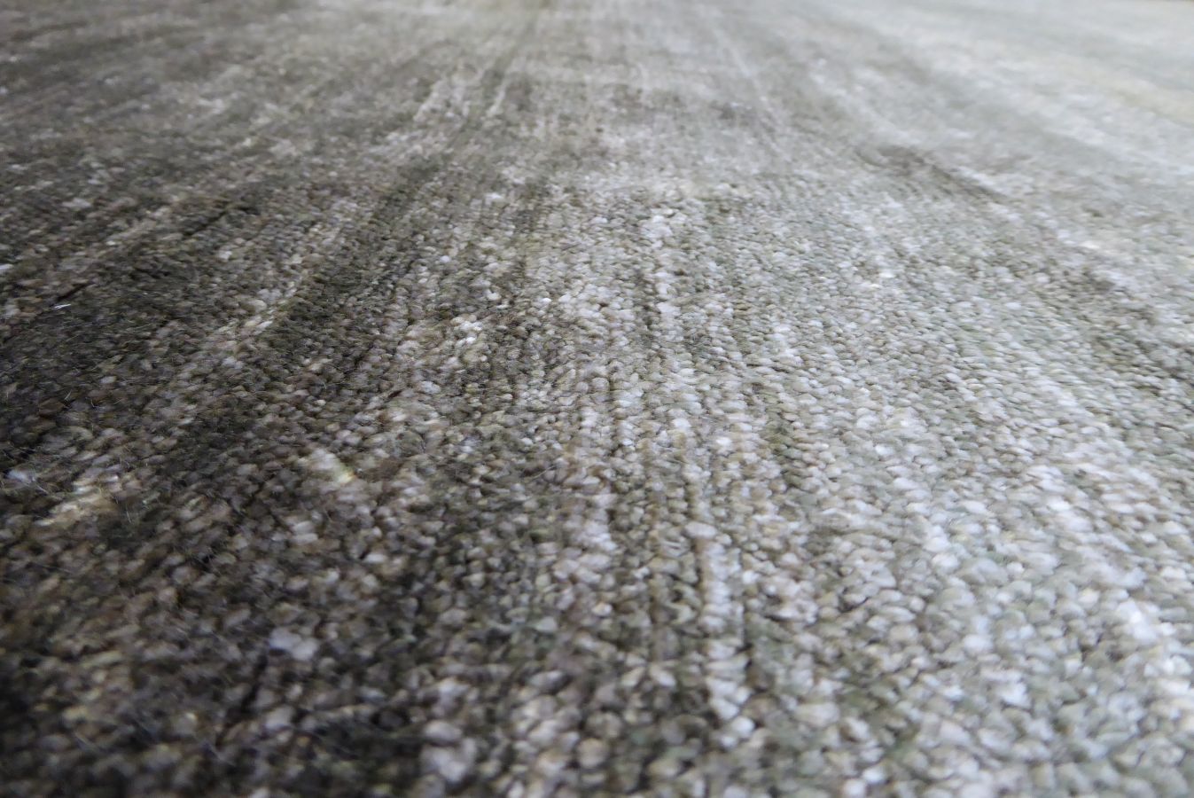 Gros plan sur la texture du tapis en soie de bambou gris-vert, fibres soyeuses et détails raffinés