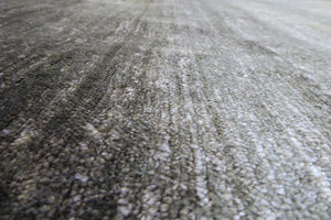 Gros plan sur la texture du tapis en soie de bambou gris-vert, fibres soyeuses et détails raffinés