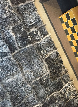 Tapis gris foncé en laine d’agneau, poil long et court, vu de bord