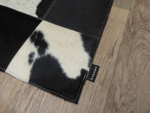 Tapis en cuir de vachette avec damier géométrique gris ivoire noir, vu en perspective depuis un coin