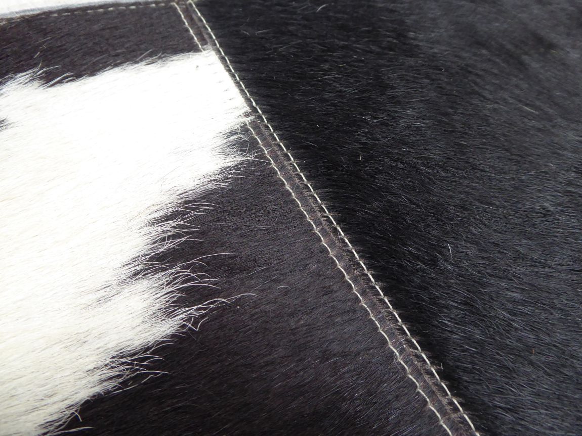 Zoom détail sur la texture du tapis en cuir de vachette, motif damier géométrique gris ivoire noir