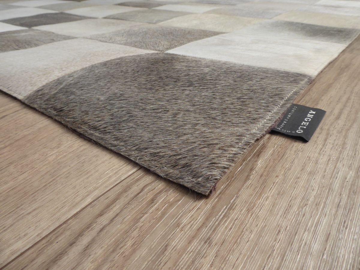Détail d’angle du tapis en cuir de vachette damier gris ivoire brun montrant la texture et la finition