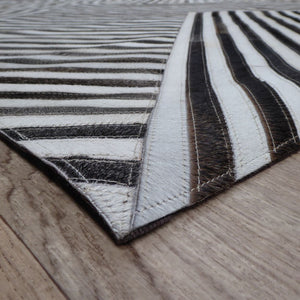 Tapis géométrique en cuir de vachette brun et blanc, vu en angle avec détails de profondeur et texture