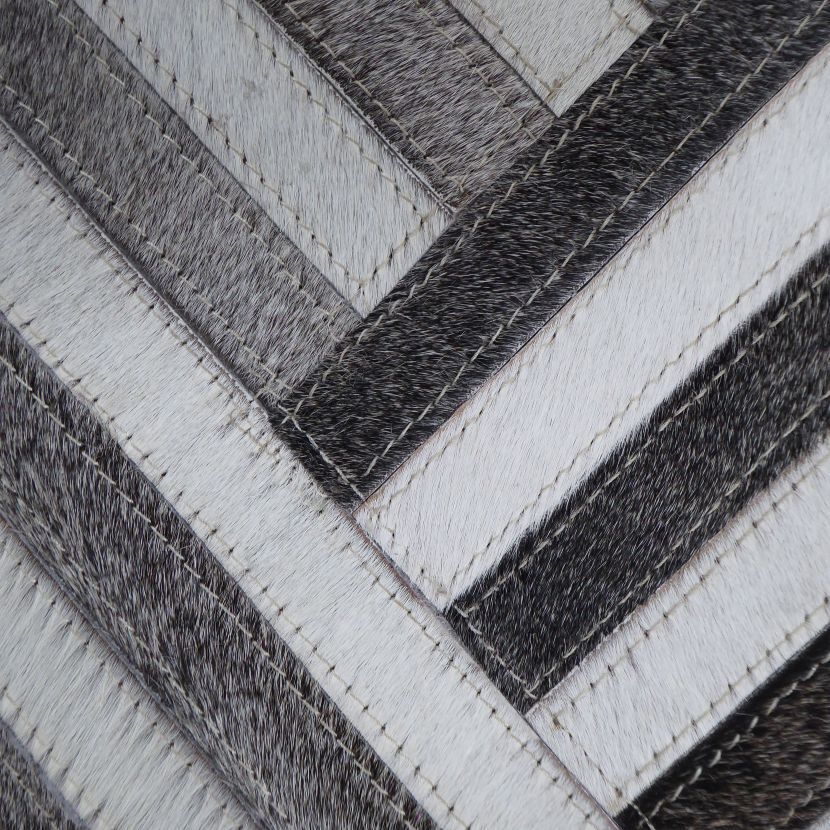 Zoom sur la matière cuir de vachette et les motifs rayés géométriques bruns et blancs du tapis