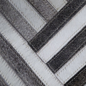 Zoom sur la matière cuir de vachette et les motifs rayés géométriques bruns et blancs du tapis