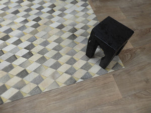 Tapis audacieux gris ivoire jaune en cuir de vachette, mis en scène avec tabouret