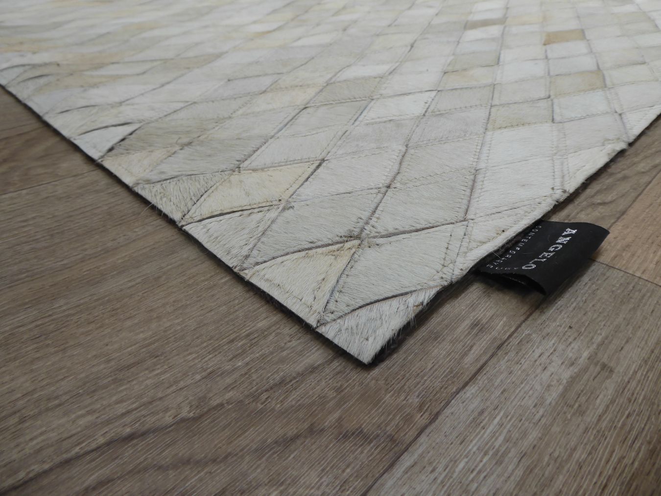 Angle du tapis en cuir de vachette avec motifs géométriques brun gris ivoire, montrant texture et bordures